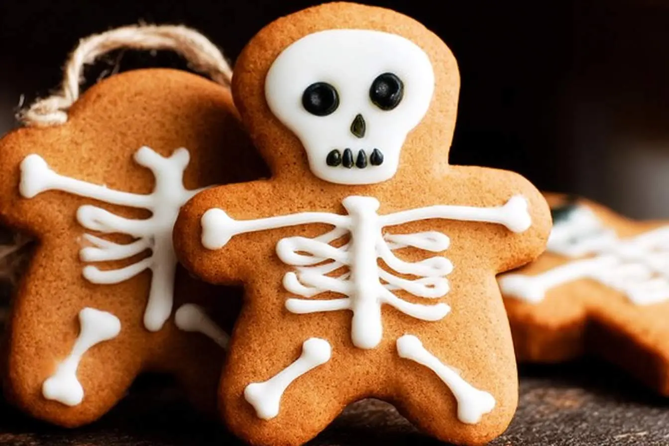Close-up of intricately decorated gingerbread Skeleton Cookies, featuring white icing bones and spooky black eyes, with one in the foreground.