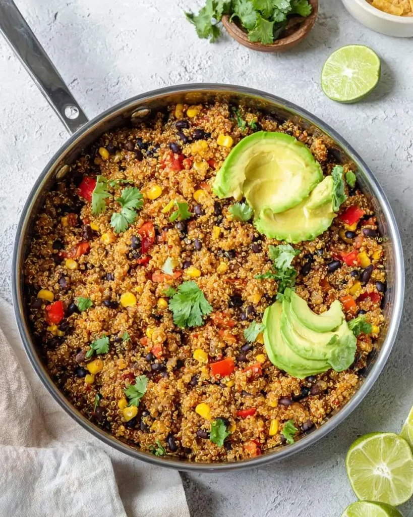 A stainless steel pan brimming with vibrant One Pan Mexican Quinoa, garnished with fresh avocado slices and cilantro.