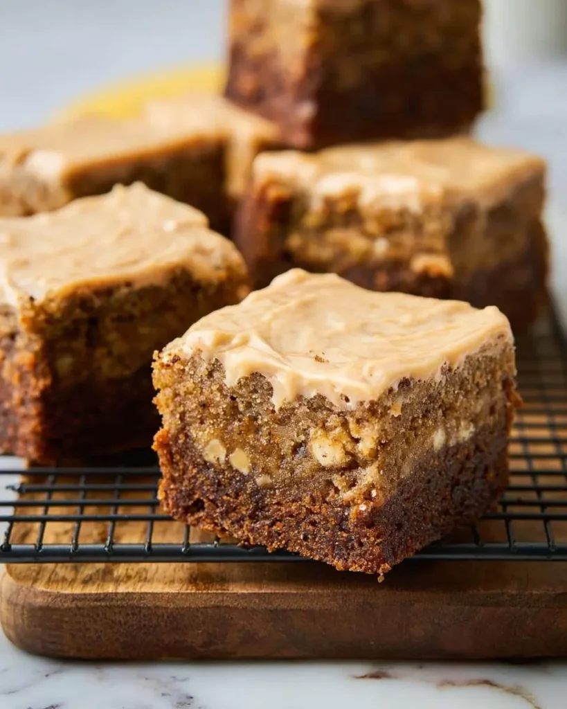 Close-up of a rich, frosted banana bread brownie with visible walnuts, resting on a cooling rack.
