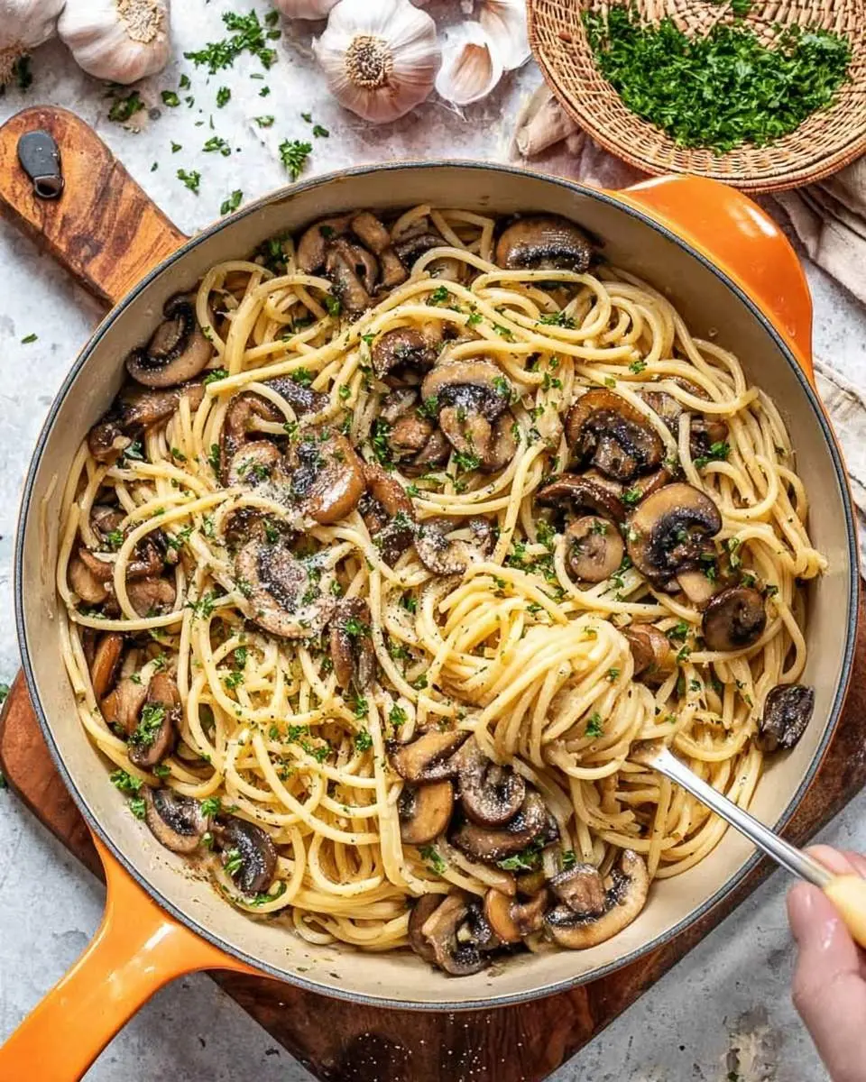 A skillet of Mushroom and Garlic Spaghetti, rich with sautéed mushrooms and fresh parsley, with a fork lifting a perfect bite.