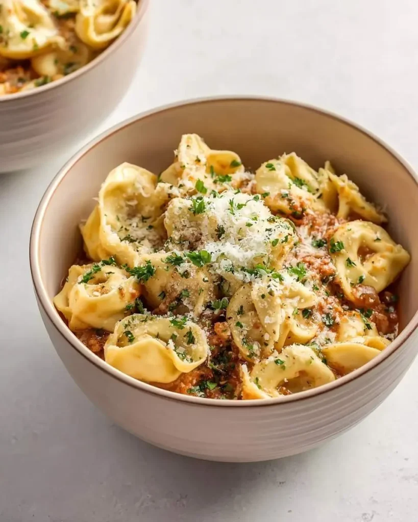A savory bowl of Crockpot Cheesy Tortellini in a hearty red sauce, generously topped with Parmesan cheese and fresh parsley.