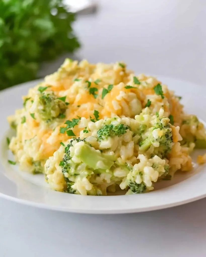 Delicious Velveeta Broccoli Rice Casserole with melted cheese and fresh parsley on a white plate.