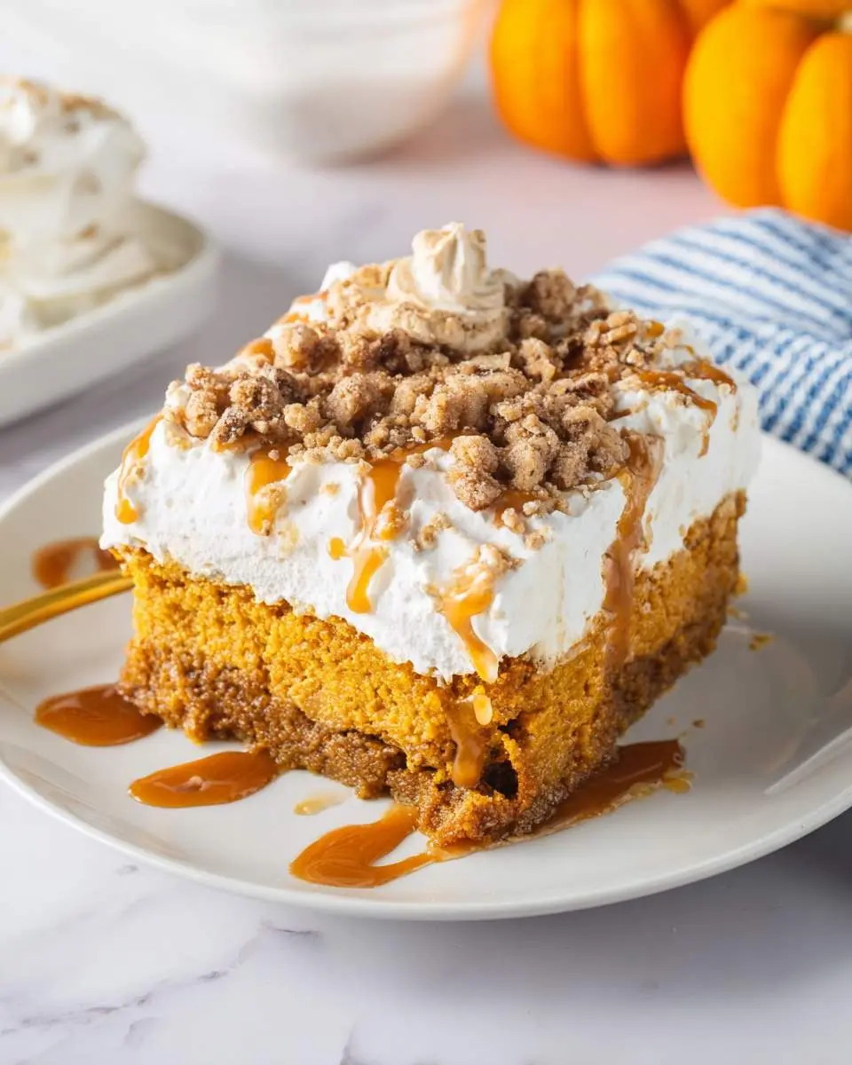 pumpkin poke cake 4 A delicious slice of pumpkin poke cake topped with whipped cream, caramel drizzle, and a crunchy streusel crumble.