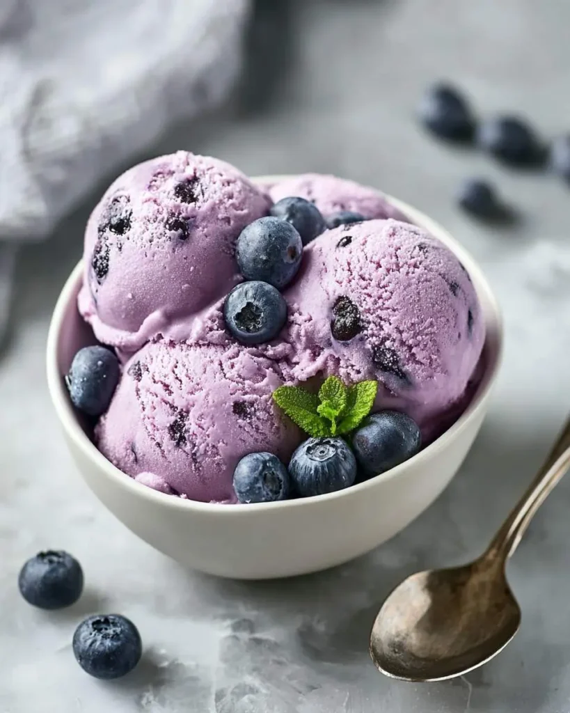Bowl of creamy Blueberry Ice Cream with Cottage Cheese topped with fresh blueberries and mint.