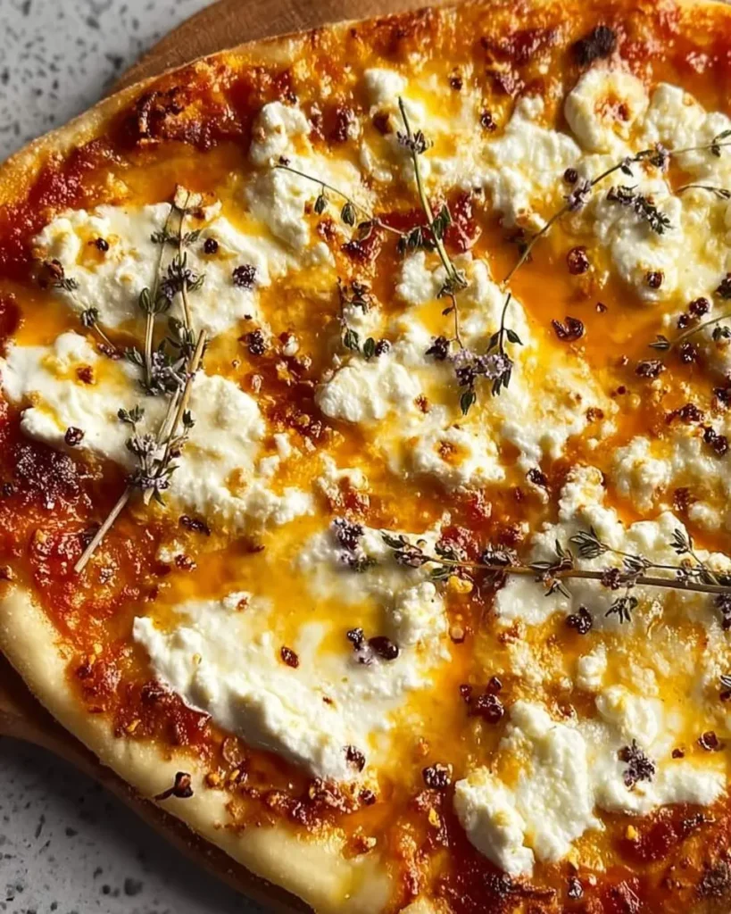 Hot Honey Ricotta Pizza topped with creamy ricotta, fresh thyme, and drizzled with spicy honey on a golden crust.