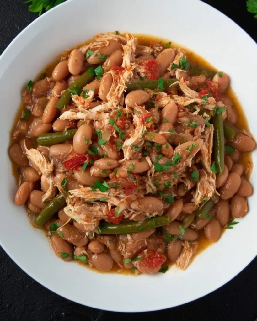A bowl of Jalapeño Beans with Shredded Chicken featuring tender white beans, green beans, and shredded chicken in a savory tomato-based broth.